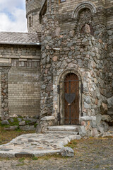 Fototapeta na wymiar Wall of stone castle, door with wrought-iron lattice