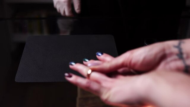 Woman brings golden ring to pawnshop owner to sell it for money. Closeup of man examining jewel with magnifying glass. Theme of pawnbrokers and their business. Lady removes ring from hand to sell it.
