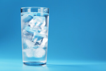 Glass with water and ice cubes on a blue background