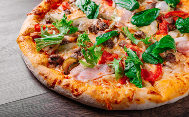 Pizza with Mozzarella cheese, Bolognese sauce, minced meat, bacon, tomato and vegetables. Italian pizza on wooden background.