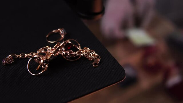 Woman brings golden rings and chains in pawnshop for selling. Man in latex gloves takes the jewelry away and gives money. Theme of businessman and professional occupation. Buying of precious metals.