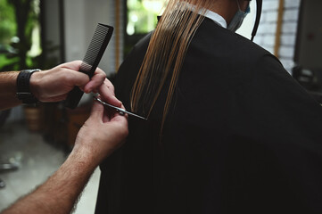 Naklejka premium Close-up haircut by a professional stylist. Hairdresser cuts hair in beauty salon