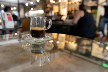 Glass espresso cup at a mirror table in a posh cafe
