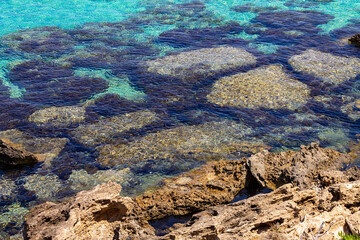 Azure clear water of the Mediterranean Sea. The rocky coast of the resort village of Protaras on the island of Cyprus. No people. Bright midday sun.