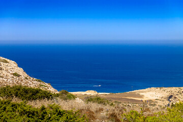 Fototapeta na wymiar A view of the Mediterranean Sea of Cyprus from the viewpoint of Capo Greco National Park. A tourist motor boat is visible in the distance.