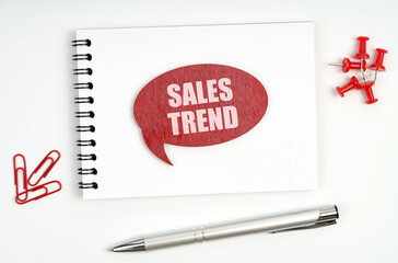 On the table there are stationery, a notebook and a red sign with the inscription - Sales Trend