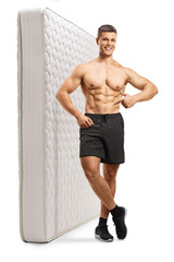 Obraz premium Full length portrait of a young shirtless man leaning on a mattress and pointing