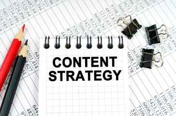 On the table are reports, pencils and a notebook with the inscription - CONTENT STRATEGY