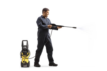Full length profile shot of a man in a uniform spraying with a pressure washer machine