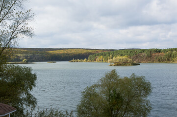 Autumn river forest landscape with cloudy sky on sunny day