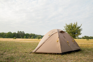 brown tent stands on the lawn on a background of sunset