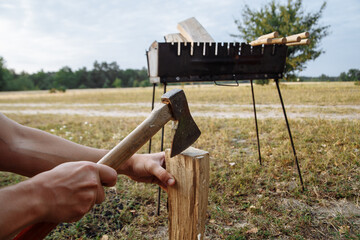 a man in a camping town chops firewood with an ax for a barbecue
