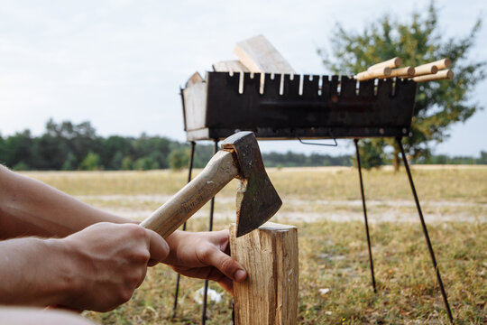 a man in a camping town chops firewood with an ax for a barbecue - Powered by Adobe