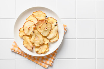Fruits pear chips on a white tiled background. Vegan dessert sugar free. View from above. Copy space.