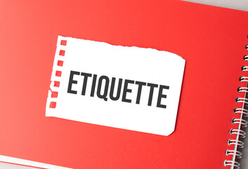 The word ETIQUETTE on torn paper on red notepad,.