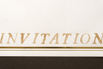 the word invitation loosely stencilled on fancy paper with space for text 