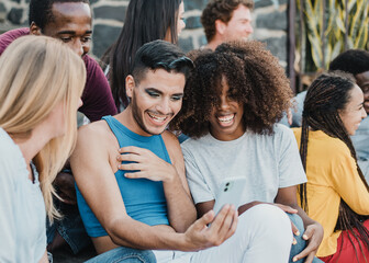 Multiracial friends having fun doing video call with mobile phone outdoor - Focus on african girl face