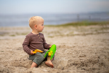 cute baby playing in the sand with sand toys on the beach.