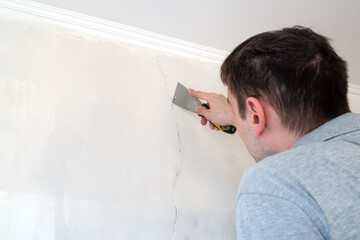 Construction man worker repairing a crack wall of a home, plastering cement on wall. Builder...