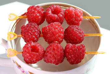 Red raspberry berries, pierced on canapes on edge of cup