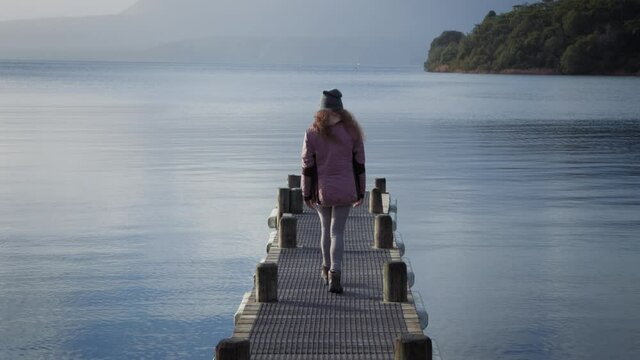 Lone girl walks onto a jetty with beautiful scenery, Rotorua, New Zealand