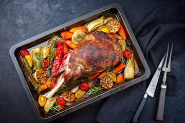 Traditional barbecue lamb shoulder with vegetables and chili served as top view on a rustic metal...