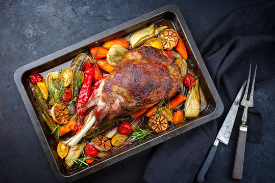 Traditional barbecue lamb shoulder with vegetables and chili served as top view on a rustic metal tray
