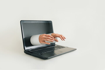 Male hands from laptop screen typing on keyboard. Remote work, e-commerce, virtual transactions, online education or social network idea. Minimal virtual, surreal, abstract scene on beige background.