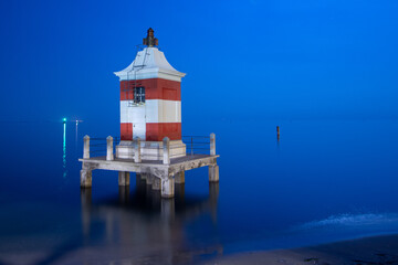 Fototapeta na wymiar Lignano Sabbiadoro, red lighthouse at night