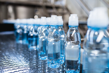 Bottling plant - Water bottling line for processing and bottling pure spring water into blue bottles. Selective focus.