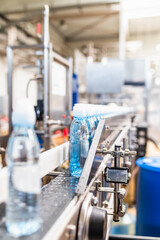 Bottling plant - Water bottling line for processing and bottling pure spring water into blue bottles. Selective focus.