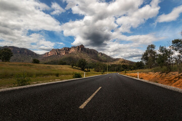 road leading to a mountain with clouds