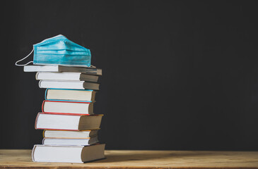 back to school during covid pandemic pile of books and medical mask
