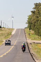 Busy route in a small town in Uruguay, with some windmills at the end of it