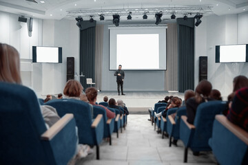 speaker standing near the big screen during a business seminar.