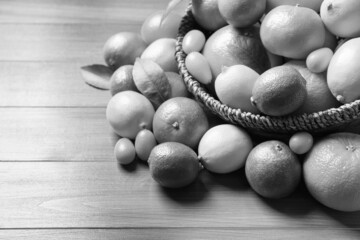 Different citrus fruits on wooden table. Black and white tone