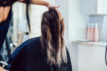 Fototapeta premium Beautiful hairstyle of young woman after dyeing hair and making highlights in hair salon.