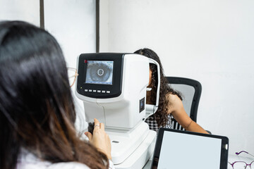 Una mujer medico de la salud visual realizando un examen de la vista a una paciente con maquinas especiales - obrazy, fototapety, plakaty