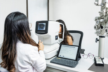 Una mujer medico de la salud visual realizando un examen de la vista a una paciente con maquinas especiales - obrazy, fototapety, plakaty