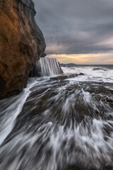 water flowing over the rocks at sunrise on the coast