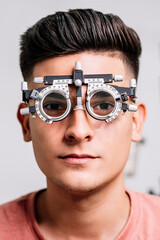 Primer plano de un Joven hombre con unas gafas de medición para realizar exámenes de la vista por el oftalmólogo 