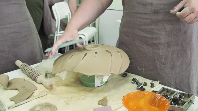 Woman hand potter making clay monstera leaf in pottery workshop studio. Process of creating ceramic vase. Handmade, hobby art and handicraft concept