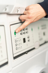 Close-up view of a hand about to press the green start button of the washing machine