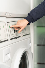 Close-up view of a hand about to press the green start button of the washing machine