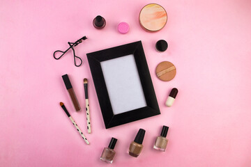 Obraz na płótnie Canvas Set of women's beauty accessories. Brush, face powder, lipstick, eyelash curler, nail polish, and a black photo frame on a magenta background. And space for your creations.