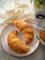 Traditional breakfast - two croissants, jam, a cup of coffee. White silk tablecloth. Home kitchen. Restaurant, hotel business, cafe. Low angle view. Close-up. Careful viewing.