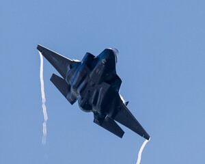 Bottom view of a F-35 Lightning II  with afterburner on and condensation trails at the wing’s tip