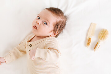 Little baby boy on white bed with a beige sheet. Happy childhood concept and hair accessories 