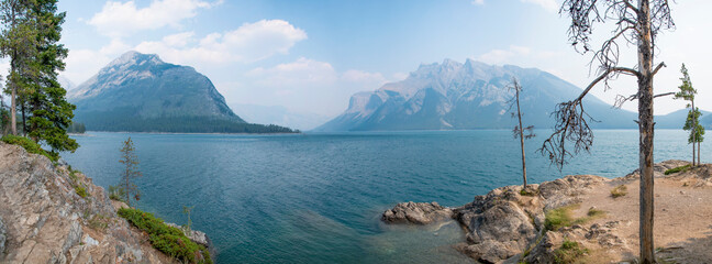 A view of Lake Minnewanka in Banff National Park, Alberta, as seen from a small alcove in its shore looking out towards the Canadian Rocky Mountains.