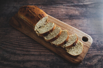 vegan homemade bread made with soy milk and herbs on wooden cutting board on rustic wooden background, healthy plant-based food